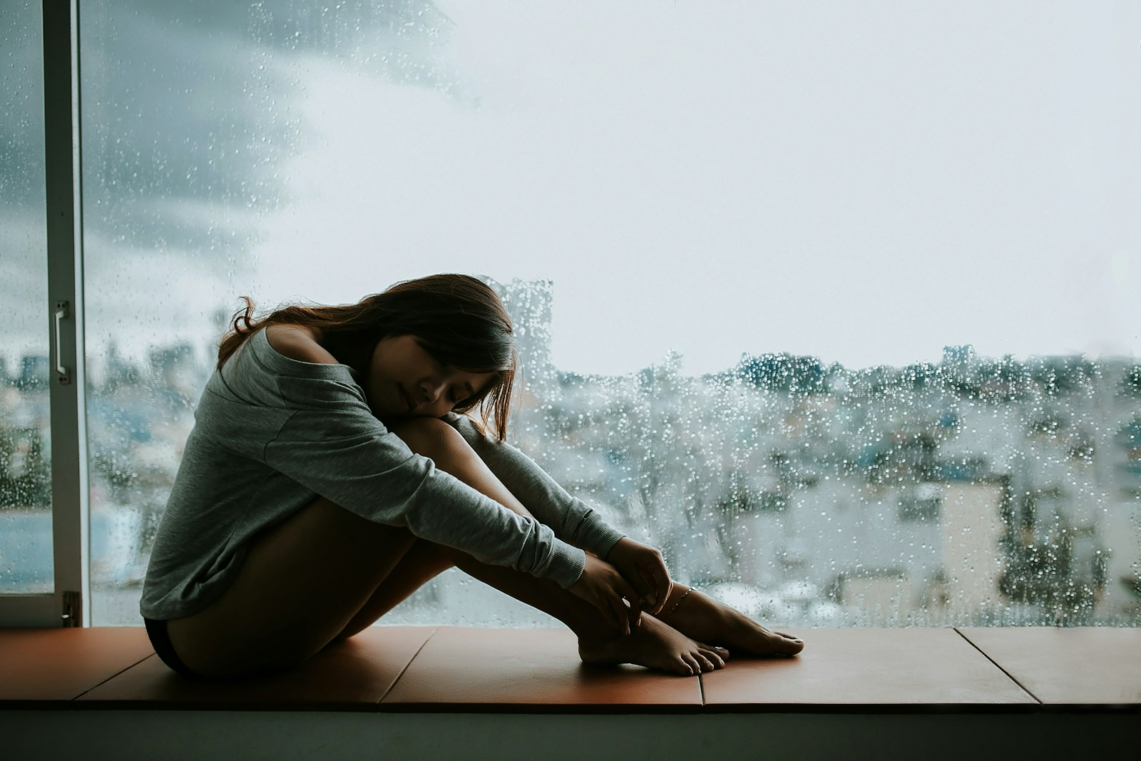 woman at rainy window wondering if its brain fog vs laziness