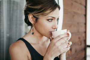 overcoming brain fog, woman leaning on wall drinking coffee